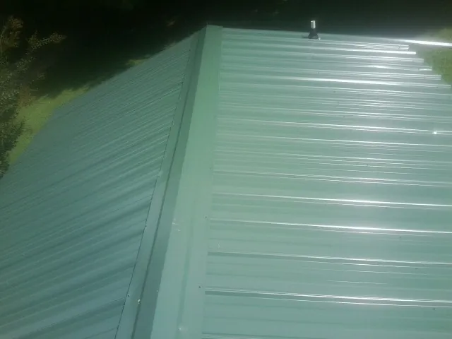 New green metal panels meeting at the ridge of a roof — Flat Roof Repair work by our crew in Port Townsend