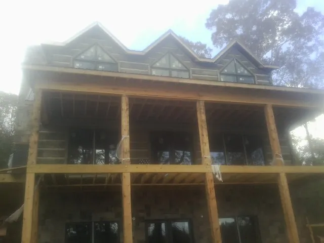 Dormers and porch framing on a large log home under construction — Roof Coating work by our crew in Port Townsend