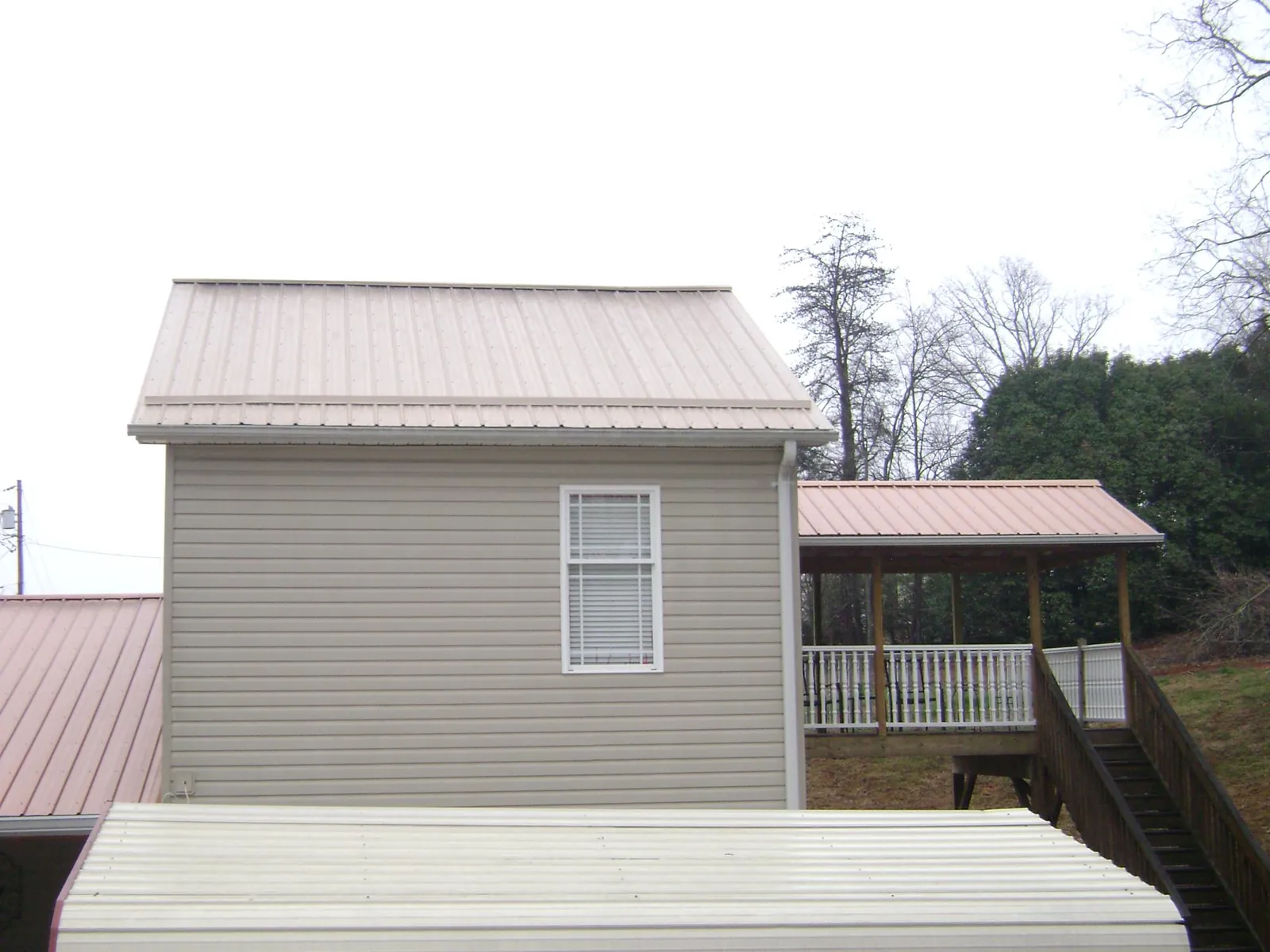 Tan metal roofs on a two story addition and attached porch, from a Roof Replacement job in Port Townsend