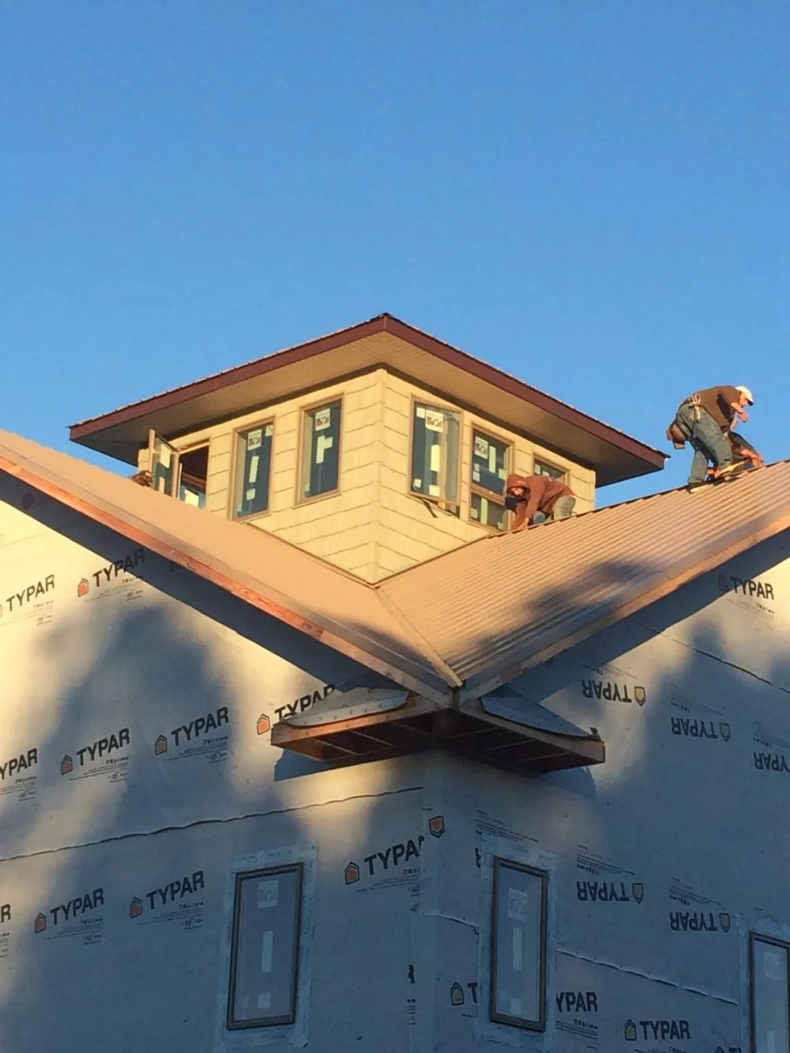 Roofers working around a rooftop cupola on a new metal roof at sunset — Roof Waterproofing in Port Townsend by Roofing Brothers